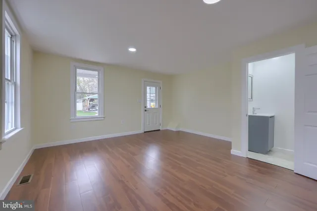 an empty room with wooden floor and windows