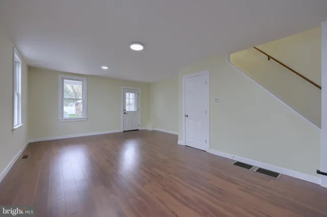 a view of an empty room with wooden floor and window