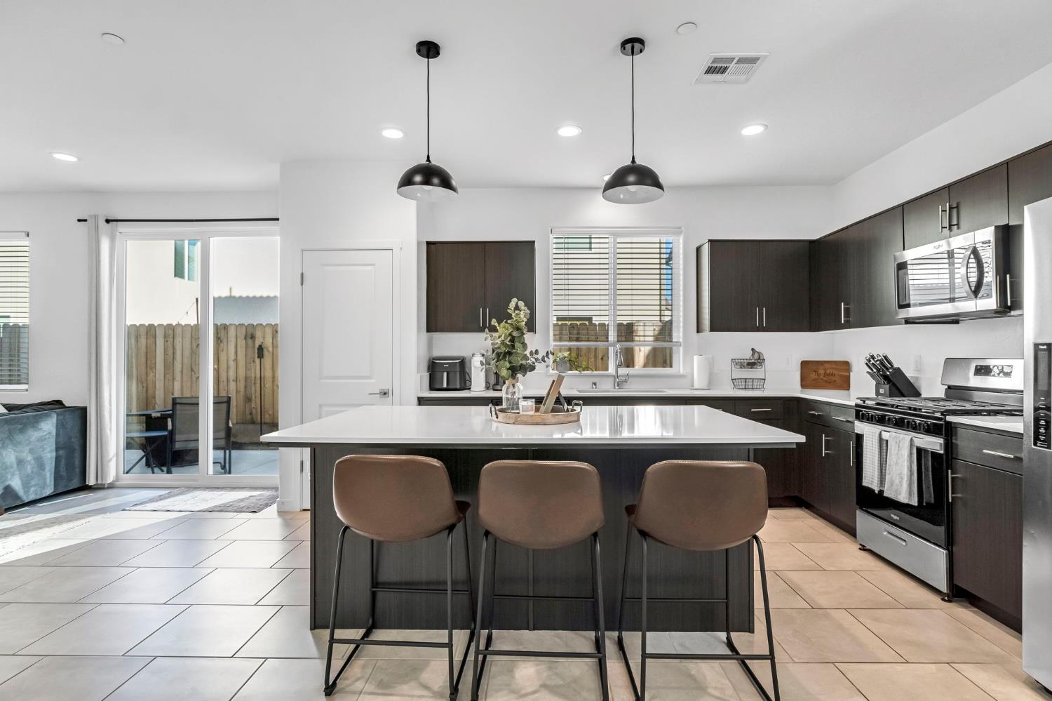 367 Talus Way South Madera, CA 93636 - Photo 9 of 40 a kitchen with stainless steel appliances a dining table chairs sink and microwave