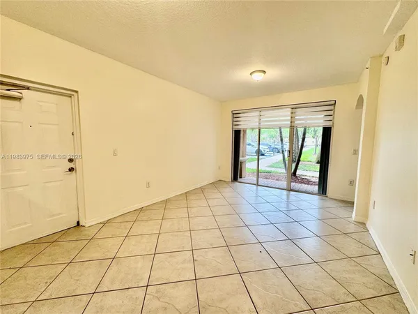 a view of a livingroom with wooden floor and a refrigerator in a bathroom