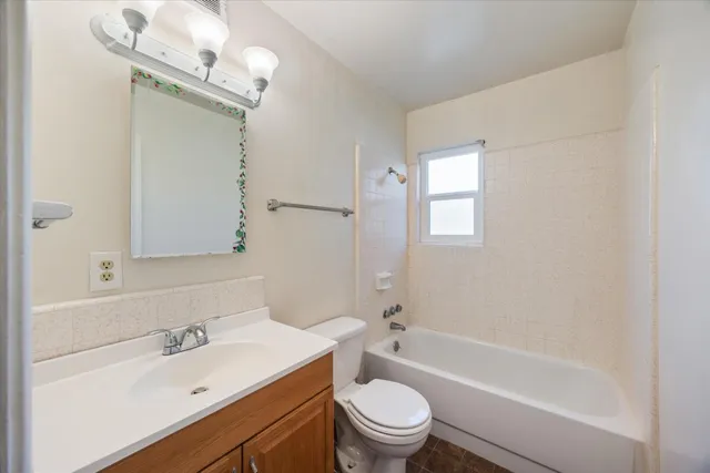 a bathroom with a bathtub shower sink vanity mirror and toilet
