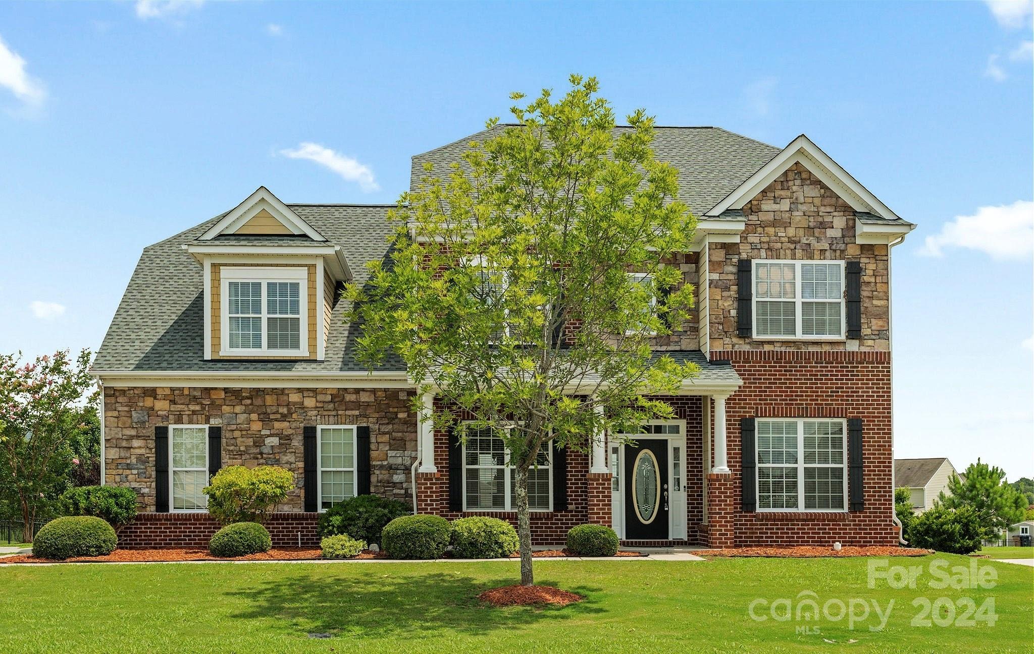 a front view of a house with a yard and trees