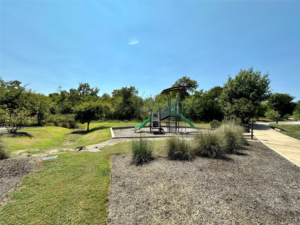 8600 Cumbrae Lane Austin, TX 78744 - Photo 25 of 29 Community play area with a lawn and view of wooded area