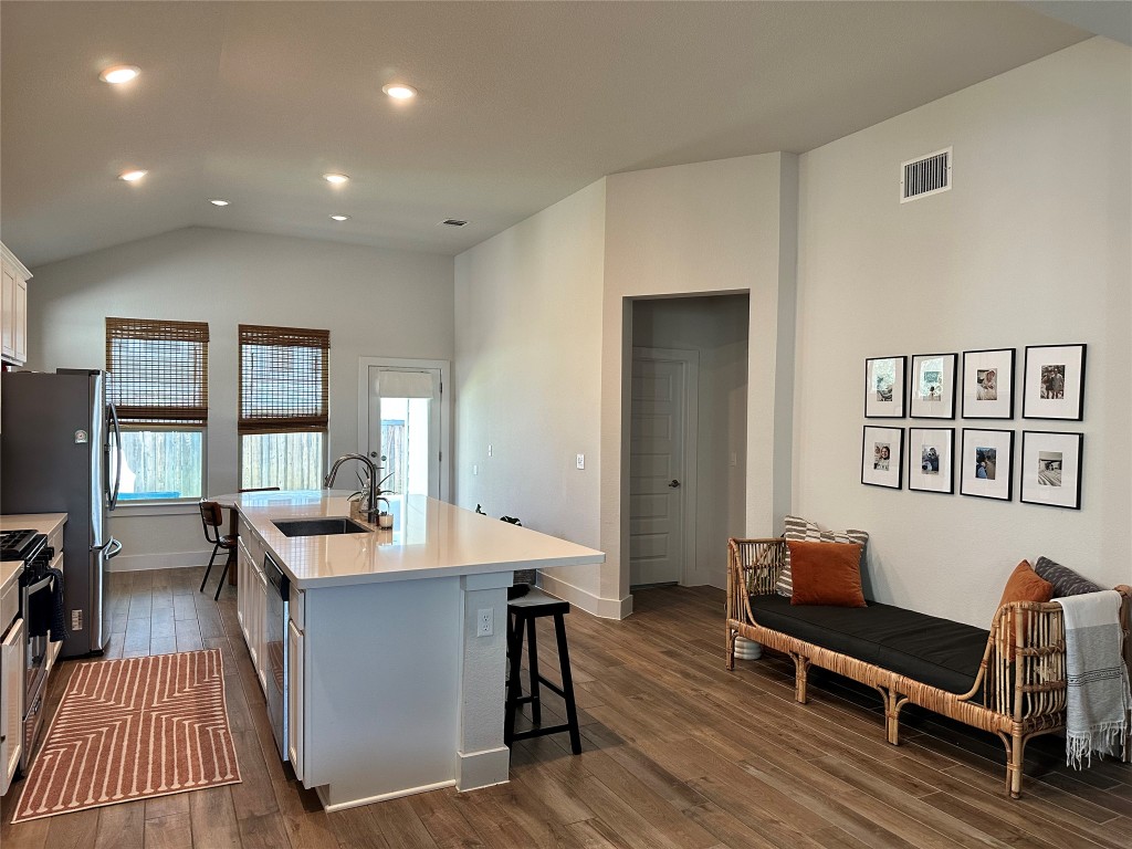 8600 Cumbrae Lane Austin, TX 78744 - Photo 5 of 29 Kitchen featuring a kitchen island with sink, dark wood finished floors, recessed lighting, a kitchen breakfast bar, and vaulted ceiling