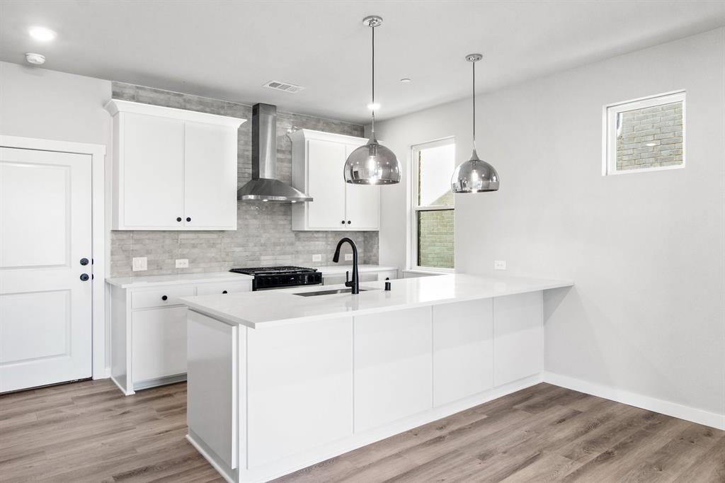 2020 Aldrich Road Celina, TX 75009 - Photo 14 of 40 a kitchen with stainless steel appliances granite countertop a sink a stove a refrigerator and white cabinets with wooden floor