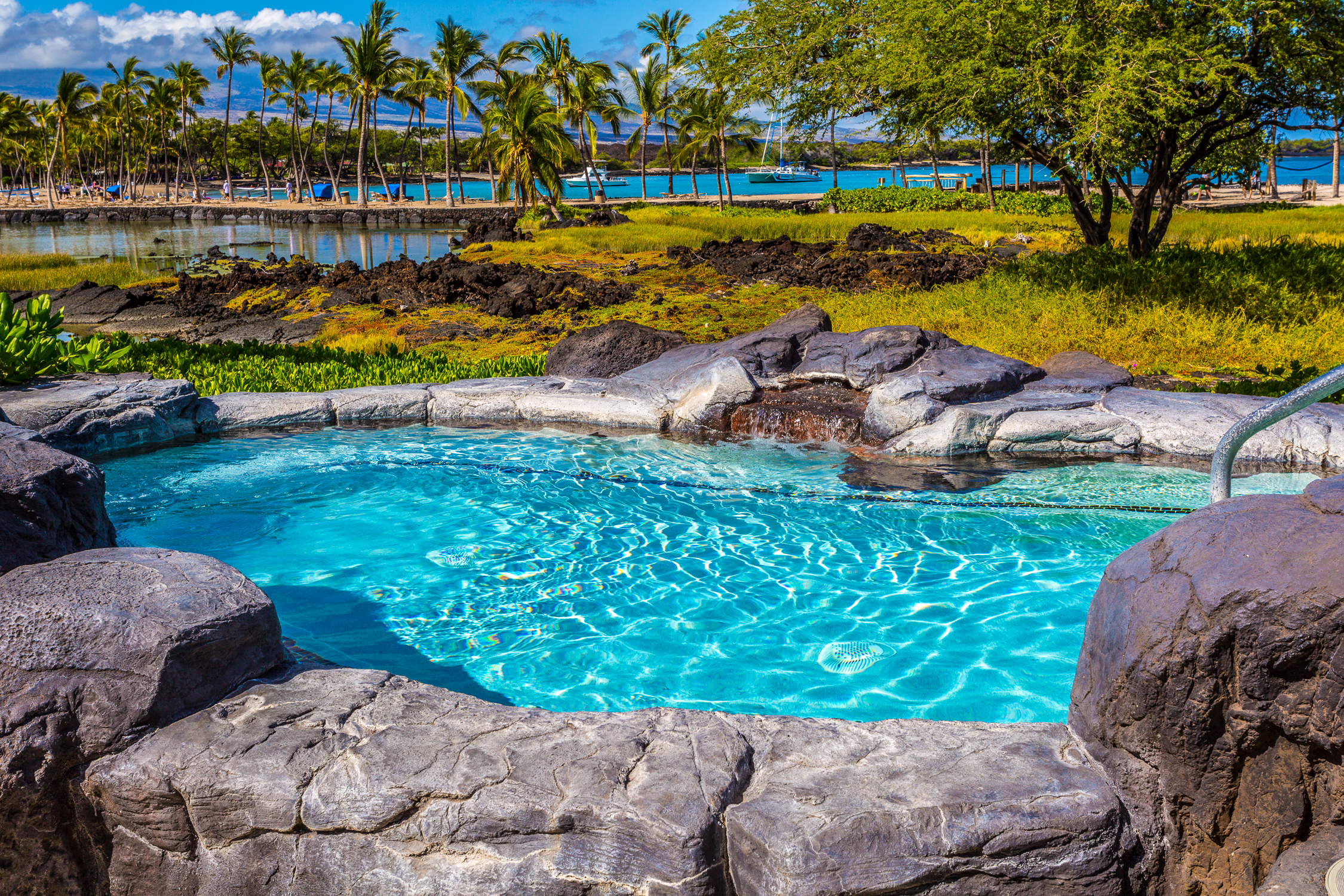 69-1000 Kolea Kai Circle, Unit 9E Waikoloa, HI 96738 - Photo 17 of 27 a view of a lake with lawn chairs and large trees