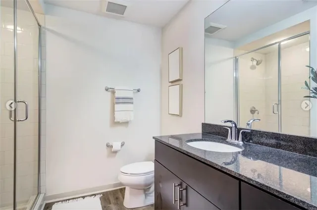 a bathroom with a granite countertop sink toilet and shower