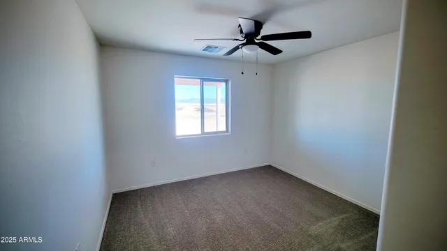 an empty room with a window and a ceiling fan