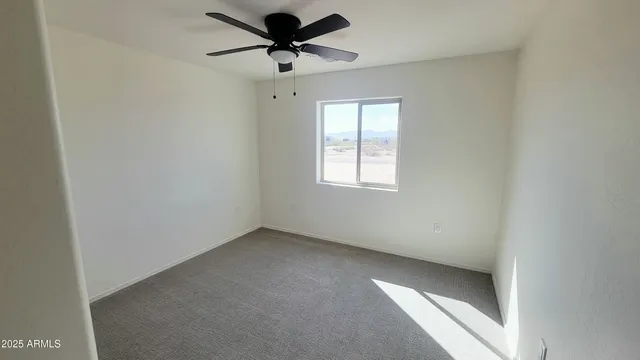 an empty room with a window and a fan