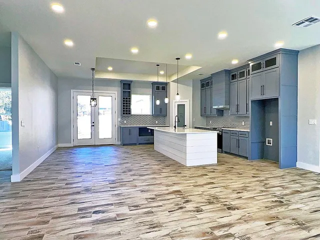 a large kitchen with kitchen island a sink dishwasher stove with wooden floor and cabinets