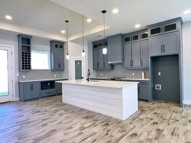 a large white kitchen with kitchen island a sink stainless steel appliances and cabinets
