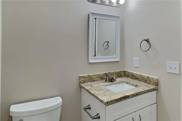 a bathroom with a granite countertop sink and a toilet