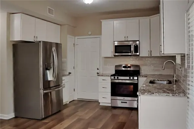 a kitchen with granite countertop a refrigerator stove and microwave