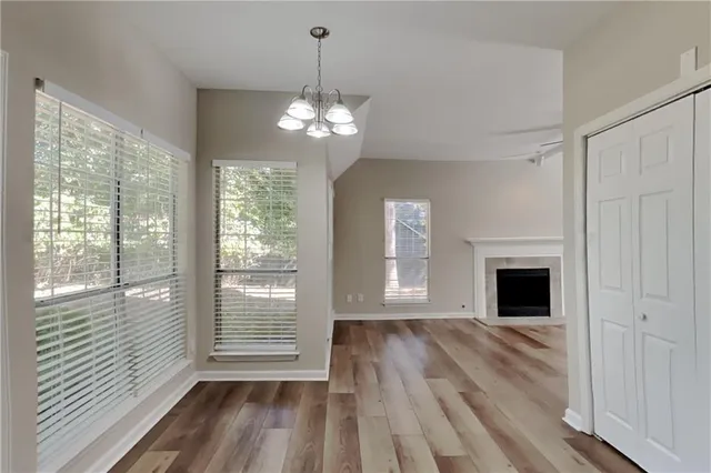 a view of a livingroom with wooden floor a ceiling fan and windows