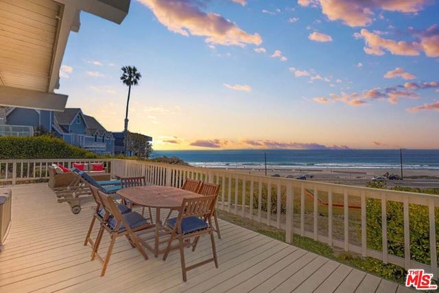 a view of a roof deck with table and chairs with wooden floor and fence