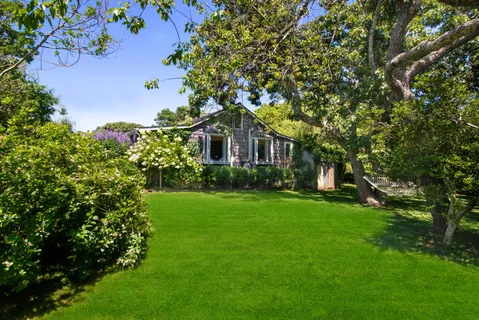 a house that has a big yard and potted plants in front of it