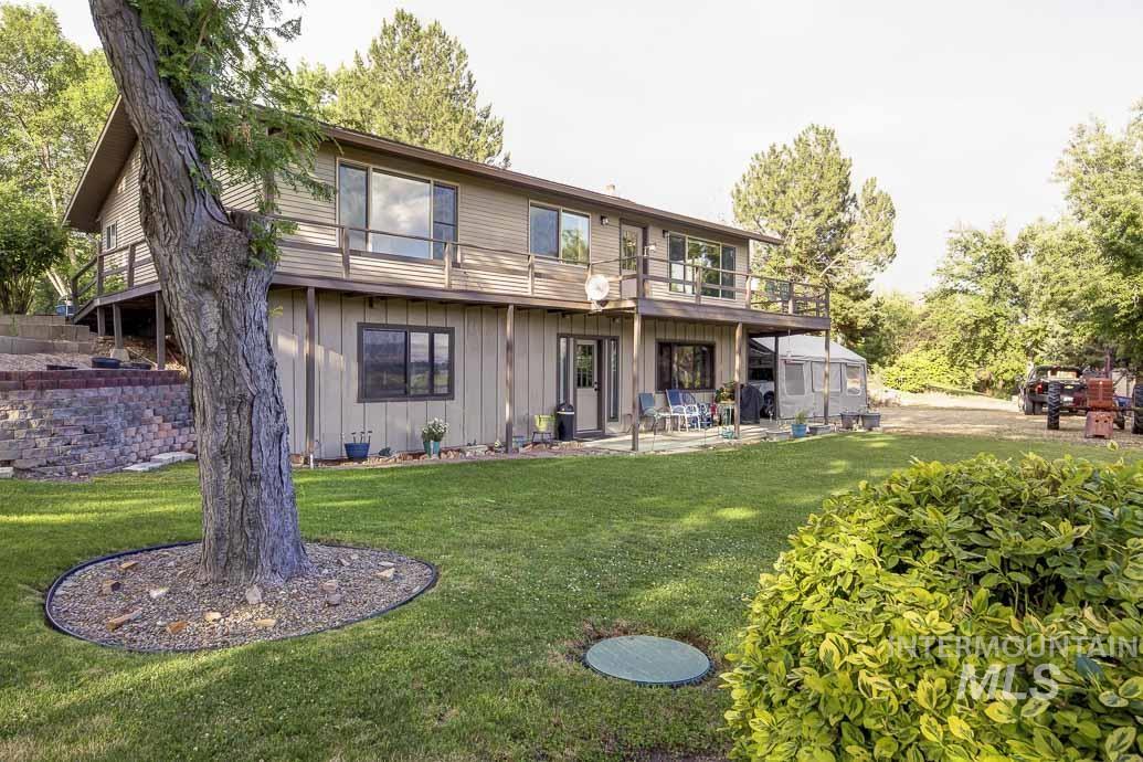 Back of house featuring board and batten siding, a lawn, a patio area, and a balcony