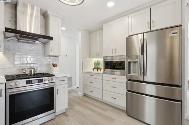 a kitchen with cabinets stainless steel appliances and wooden floor