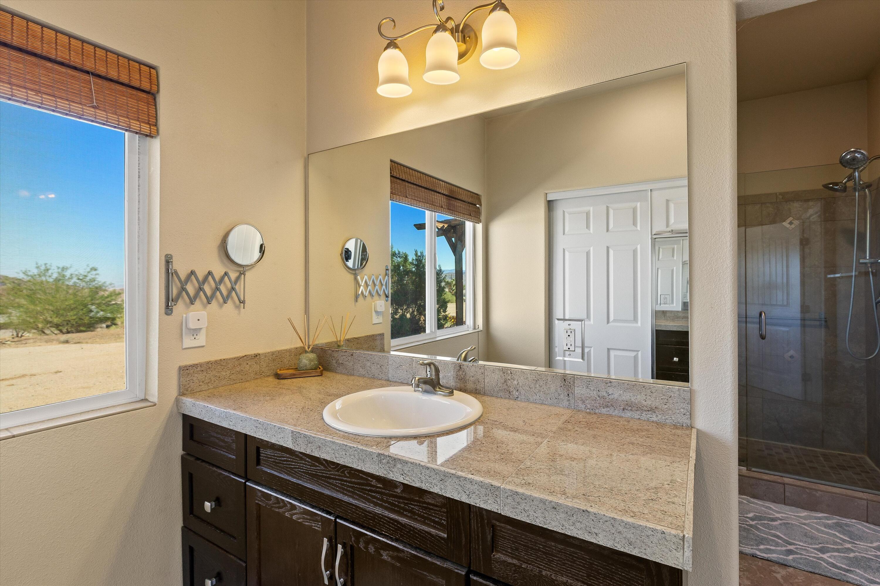 60377 Pueblo Trail Joshua Tree, CA 92252 - Photo 49 of 57 a bathroom with a granite countertop sink a mirror and a shower