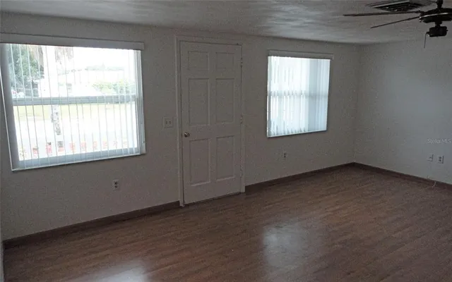 a view of an empty room with wooden floor and a window