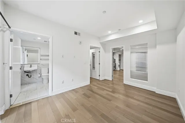 a view of a hallway with wooden floor and a bathroom
