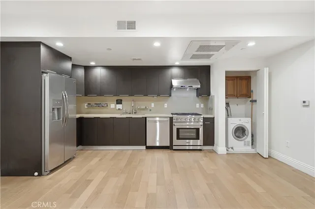 a large white kitchen with stainless steel appliances granite countertop a stove and a refrigerator
