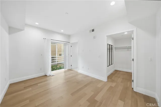 a view of an empty room with wooden floor and closet