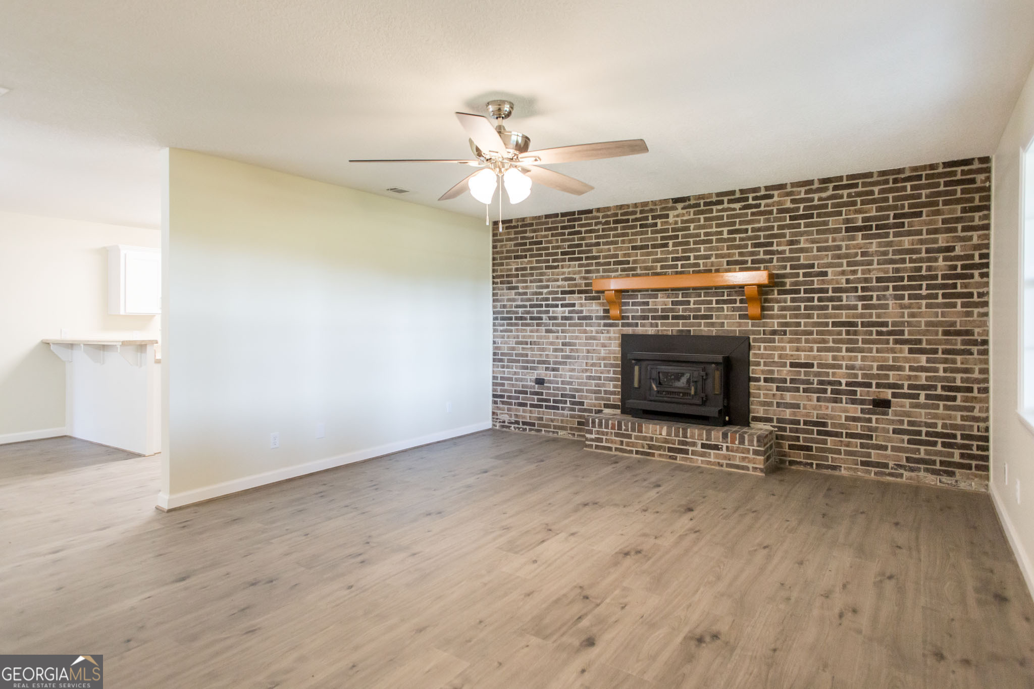 6731 Youmans Chapel Road Blackshear, GA 31516 - Photo 10 of 33 an empty room with a fireplace and fan