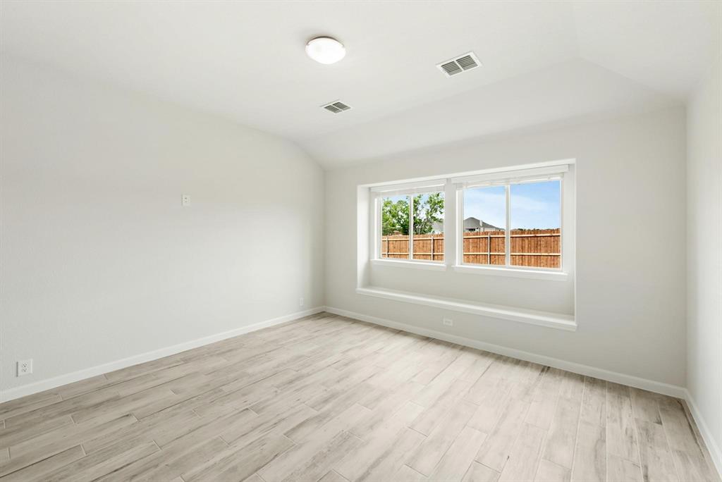 920 Elk Ridge Run Godley, TX 76044 - Photo 7 of 34 Spacious room featuring wood-finish flooring, a wide window with a built-in sill, crisp white walls, and a ceiling-mounted light fixture