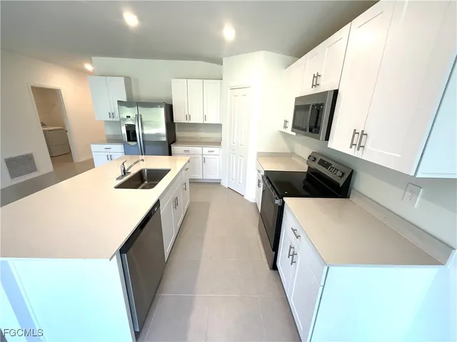 a kitchen with a sink a microwave a refrigerator and cabinets