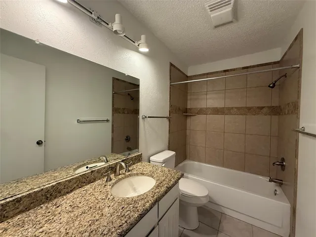 a bathroom with a granite countertop sink a toilet and shower