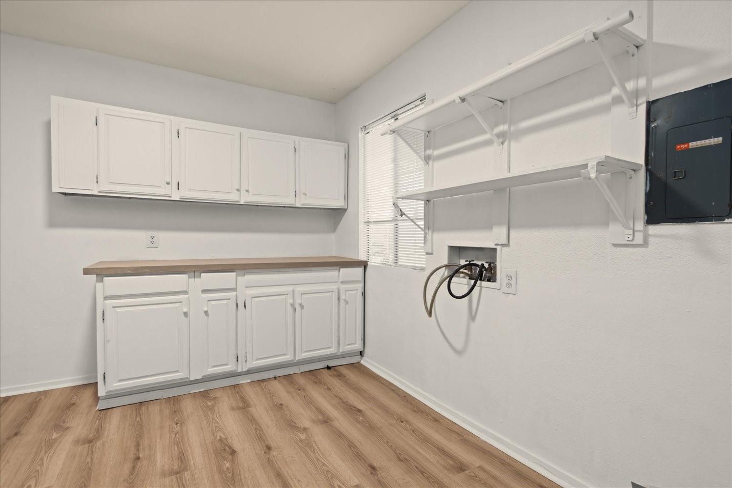 559 Demarett Drive Point Venture, TX 78645 - Photo 17 of 23 Washroom featuring washer hookup, electric panel, light wood-style floors, and cabinet space