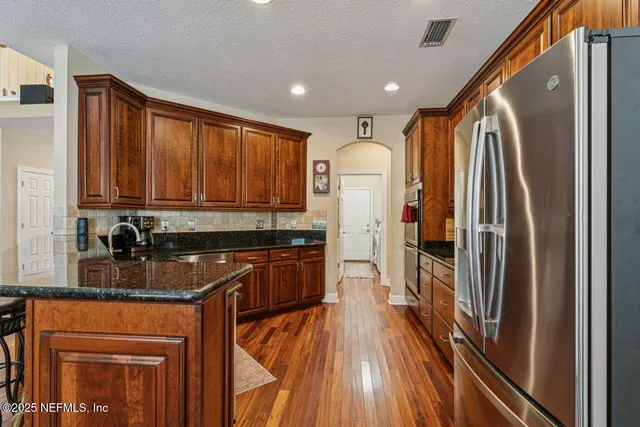 a kitchen with stainless steel appliances granite countertop a refrigerator a stove and a wooden cabinets