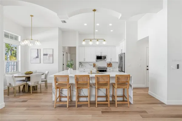 a view of a dining room and livingroom with furniture wooden floor a chandelier
