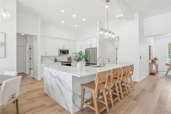a kitchen with stainless steel appliances kitchen island granite countertop a dining table chairs and sink