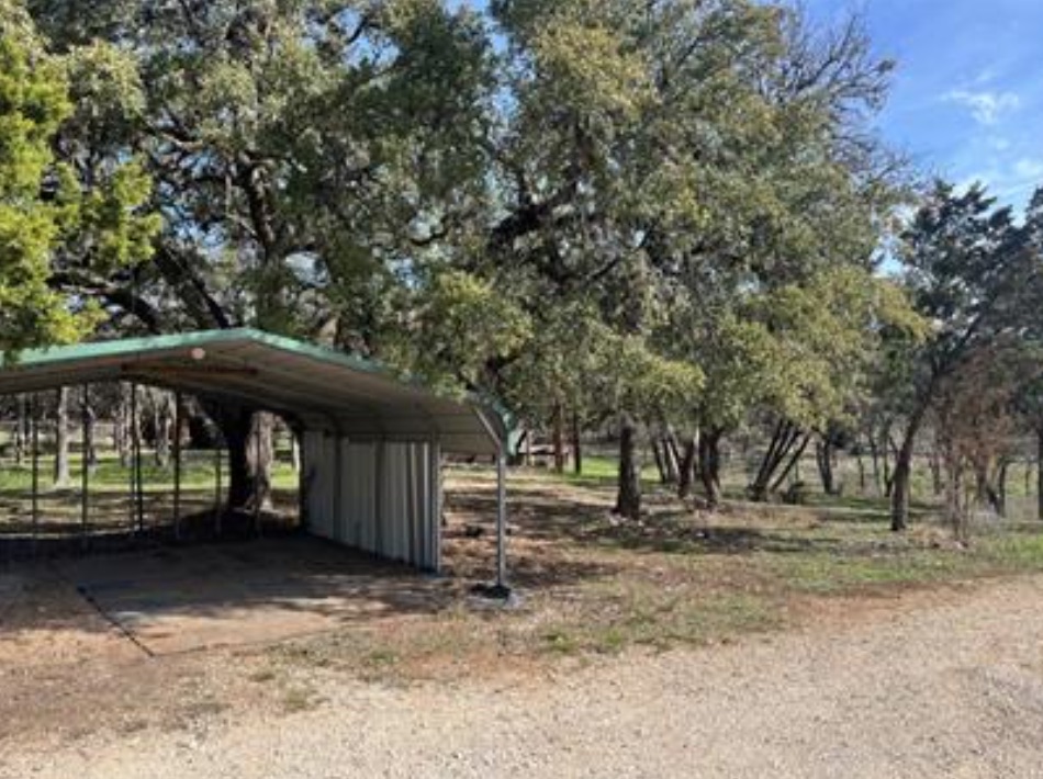 230 Six Pines Road San Marcos, TX 78666 - Photo 15 of 21 a view of a backyard with large trees and a small barn
