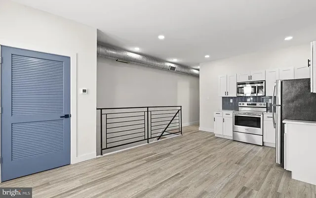 a kitchen with stainless steel appliances a refrigerator and wooden floor