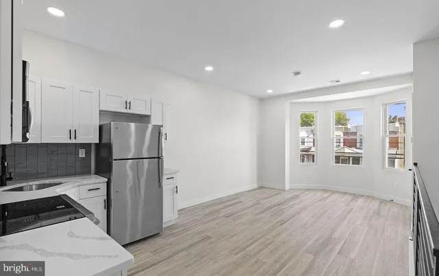 a kitchen with a refrigerator and wooden floor