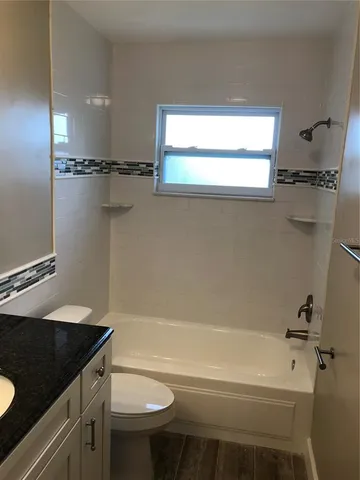 a bathroom with a granite countertop sink mirror vanity and toilet