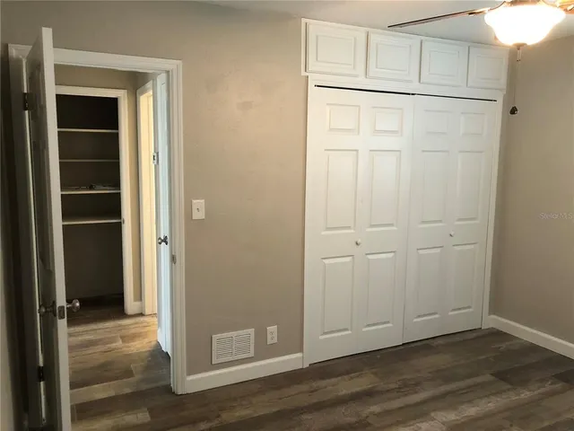 a view of an empty room with wooden floor and closet