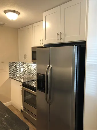 a kitchen with granite countertop a refrigerator and a stove