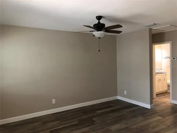 a view of a room with wooden floor and a ceiling fan