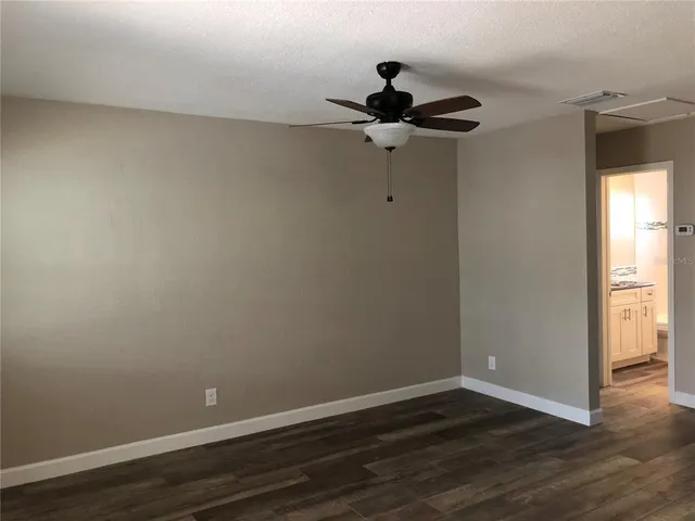 a view of a room with wooden floor and a ceiling fan