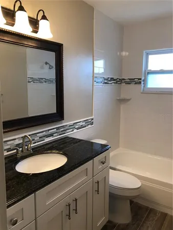a bathroom with a granite countertop sink toilet and a bathtub