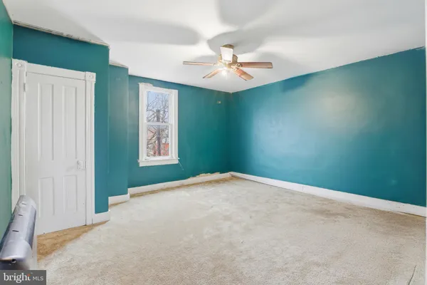 a view of a big room with carpet and a chandelier fan