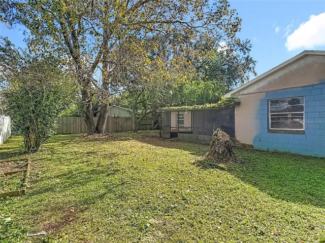 a backyard of a house with large trees and table and chairs