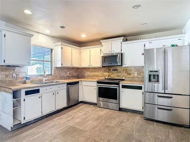 a kitchen with granite countertop a sink stainless steel appliances and cabinets