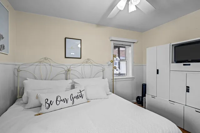 a bedroom with a bed and a flat tv screen on the dresser