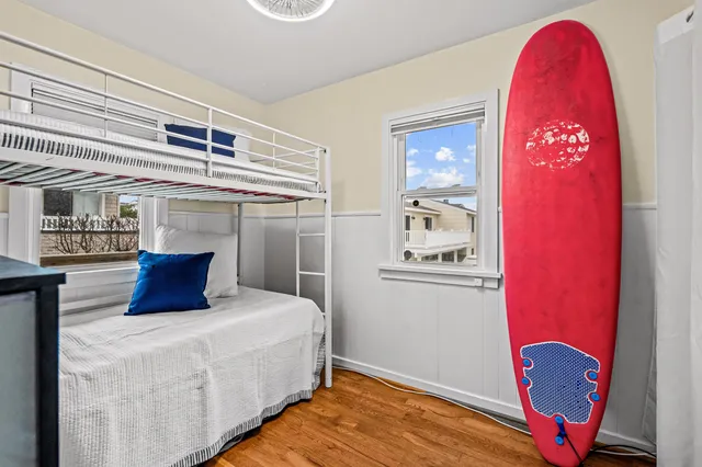 a bedroom with a bed a dresser and potted plant