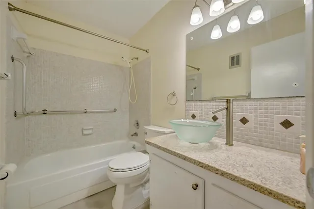 a bathroom with a granite countertop sink a toilet and shower